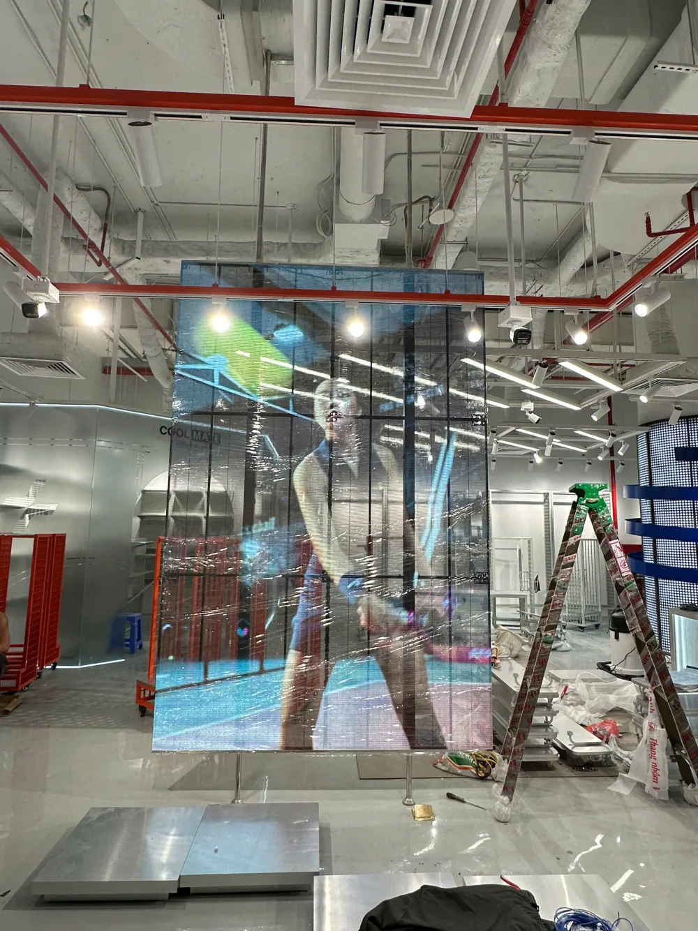Vách LED trong suốt Coolmate sau khi lắp đặt được bọc màng bảo vệ, phía sau là khu vực cửa hàng đang hoàn thiện